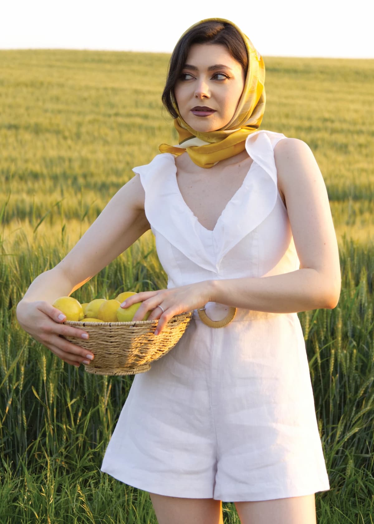Maria, pe un câmp de grâu, cu lămâi aurii într-un coș, purtând eșarfă MARLÚME din mătase naturală, ce îmbrățișează feminitatea și emoțiile, cu un rafinat aer italian.